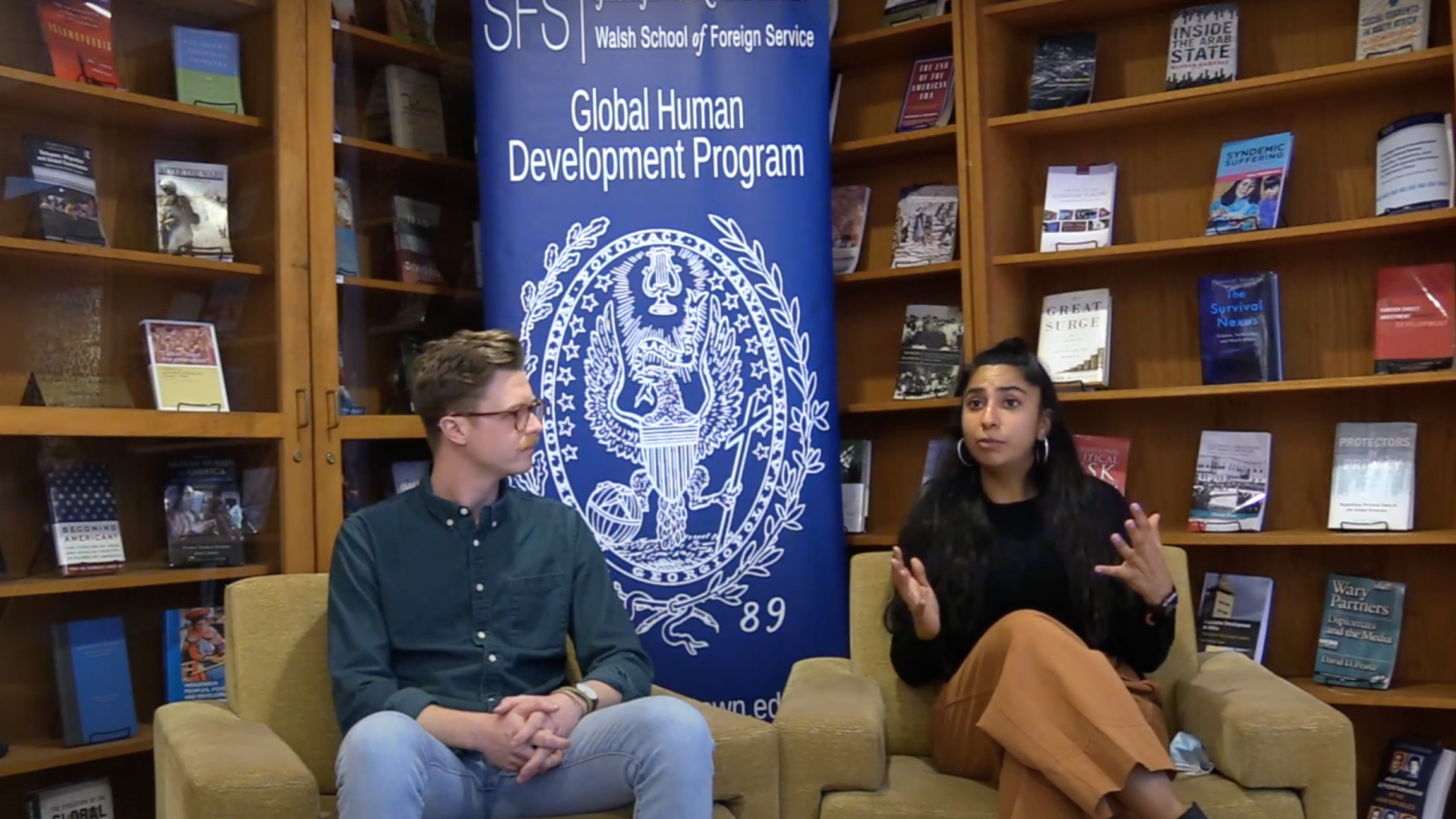 Bradley and Shirin sitting in a library in front of a GHD poster