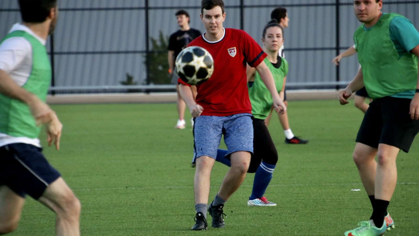 Chris eyeing a flying soccer ball in the field while surrounded by the opposing team