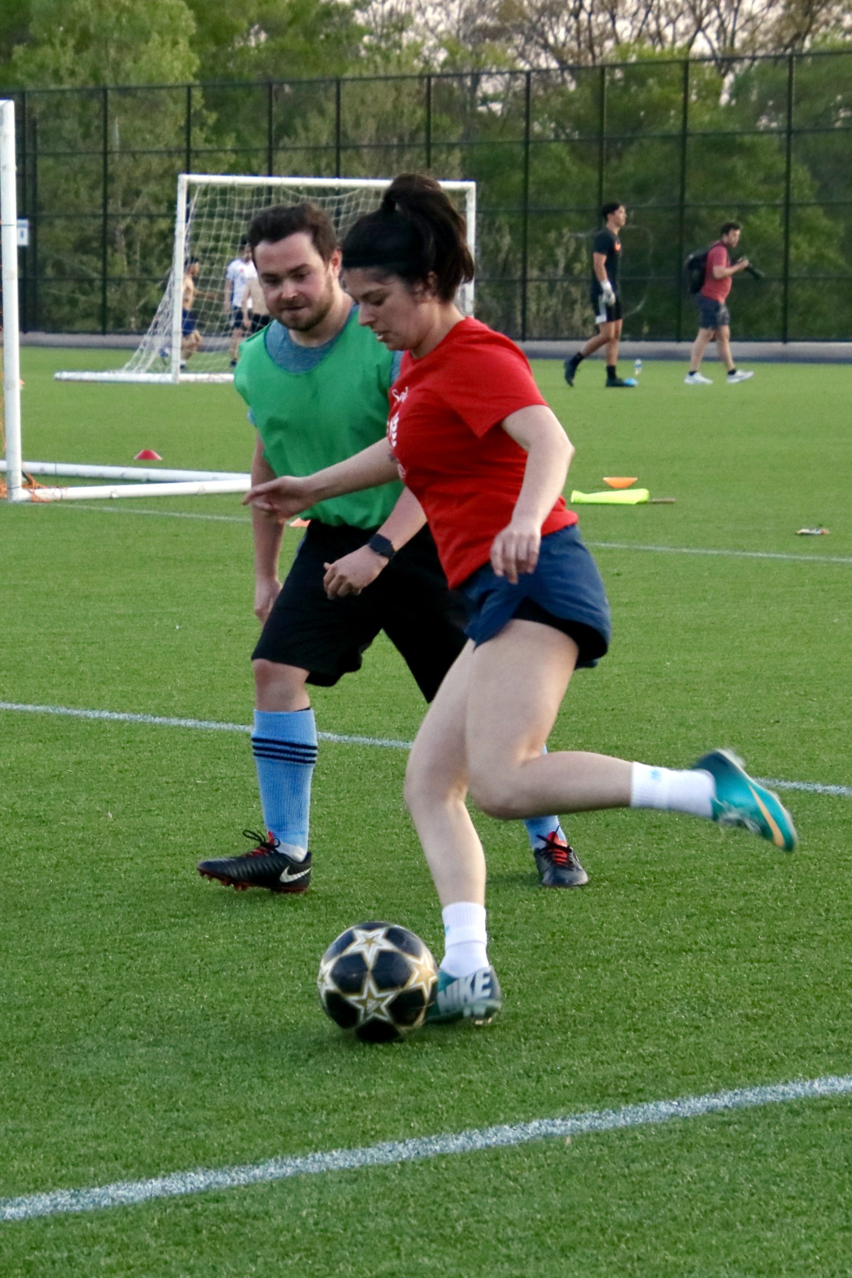 Chloe kicking a soccer ball on a field with an opposing team member behind her