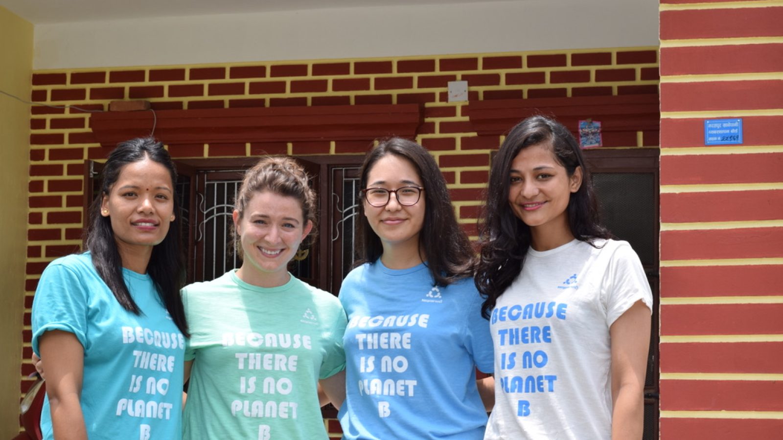 Four women standing together wearing shirts that say 