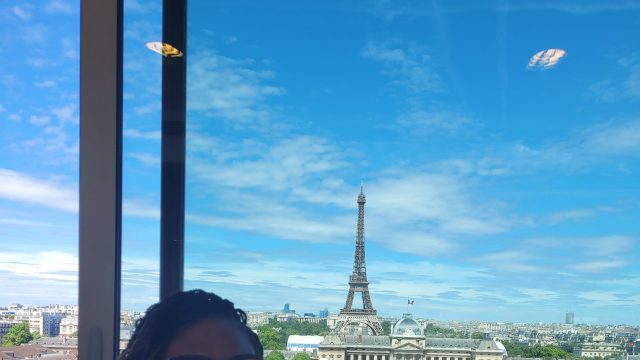 Foluyinka smiling in front of a backdrop of Paris with the Eiffel Tower