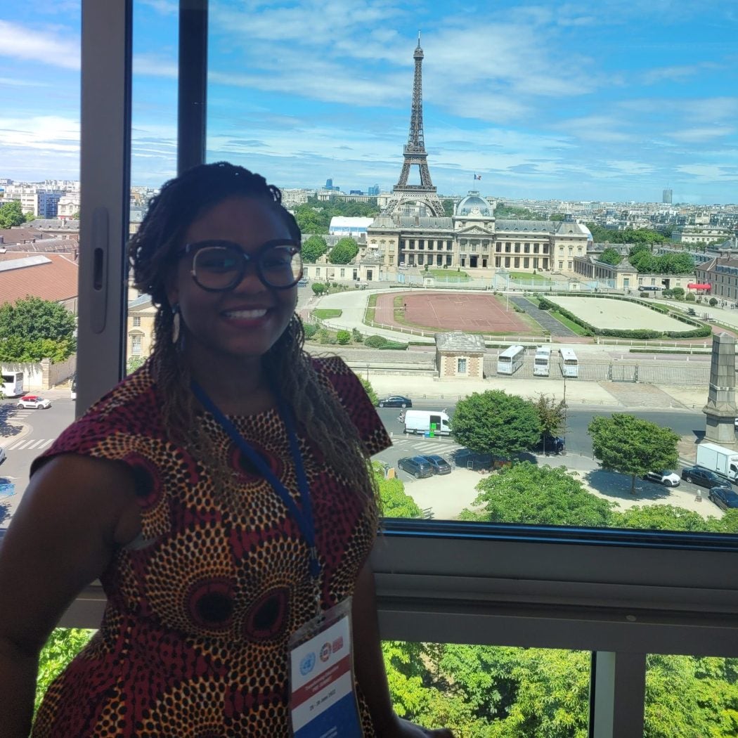 Foluyinka smiling in front of a backdrop of Paris with the Eiffel Tower