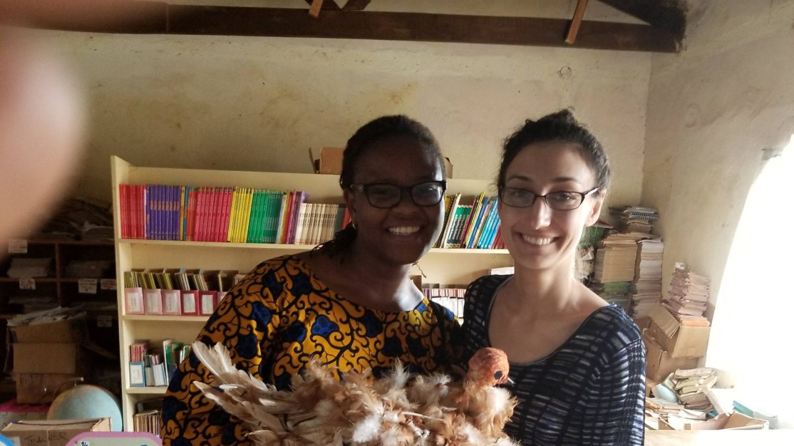 Foluyinka and her capstone partner standing in a schoolroom holding a crafted chicken